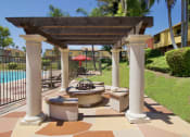 Thumbnail 29 of 30 - a patio with a fire pit and a pergola overlooking a swimming pool at Brookhollow Apartments, California