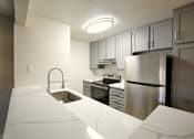 Thumbnail 3 of 30 - a kitchen with white marble counter tops and stainless steel appliances