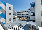Thumbnail 2 of 38 - a view of the courtyard of a building with tables and umbrellas at Harbor Terrace Apartments, San Pedro , CA 90731