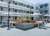Thumbnail 6 of 38 - a patio with tables and chairs and umbrellas in front of a building at Harbor Terrace Apartments, San Pedro , CA 90731