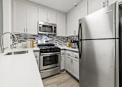 Thumbnail 13 of 38 - a kitchen with stainless steel appliances and white cabinets at Harbor Terrace Apartments, San Pedro