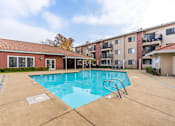 Thumbnail 2 of 13 - A swimming pool in a residential area with a building in the background.