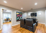 Thumbnail 11 of 13 - A living room with a poster on the wall and a row of black leather chairs.