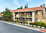 Thumbnail 6 of 13 - A building with a red roof and beige walls with a staircase leading to the entrance.
