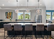 Thumbnail 6 of 21 - a kitchen with an island and chairs and a refrigerator
