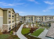 Thumbnail 1 of 12 - an exterior view of an apartment complex with a green courtyard