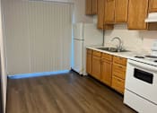 Thumbnail 3 of 7 - a kitchen with wood flooring and a white stove and refrigerator