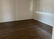Thumbnail 4 of 7 - an empty living room with wooden floors and a window