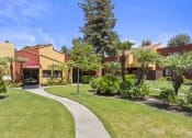 Thumbnail 25 of 30 - a sidewalk in front of a building with palm trees at Brookhollow Apartments, California