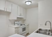 Thumbnail 13 of 30 - a kitchen with white cabinets and white appliances and a sink at Brookhollow Apartments, West Covina