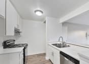 Thumbnail 20 of 30 - an empty kitchen with white cabinets and a stove and sink at Brookhollow Apartments, West Covina ,California, 91792