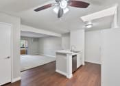 Thumbnail 22 of 30 - an empty kitchen and living room with a ceiling fan at Brookhollow Apartments, California