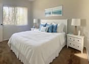 Thumbnail 5 of 10 - A bedroom with a large bed, a nightstand, and a window with curtains.