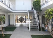 Thumbnail 5 of 10 - A white building with a staircase leading to the second floor.