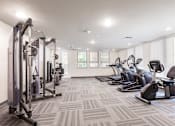 Thumbnail 6 of 17 - A well-lit gym with a variety of equipment including treadmills, stationary bikes, and weight machines.