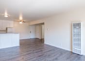 Thumbnail 5 of 16 - an empty living room and kitchen with white walls and wood flooring