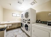 Thumbnail 15 of 20 - laundry facility room with a couple washer and dryer machines near counters