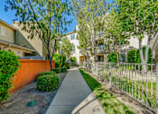 Thumbnail 4 of 20 - a walkway between two buildings with trees and a fence