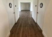 Thumbnail 36 of 44 - a look down a hallway in the club room with white walls and wood floors