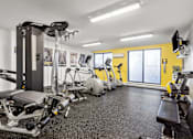 Thumbnail 4 of 20 - A gym with a variety of equipment including treadmills, stationary bikes, and weight machines.