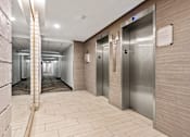 Thumbnail 6 of 20 - A long hallway with a series of elevators on the right side.