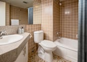 Thumbnail 6 of 8 - A bathroom with a toilet, sink, and bathtub.