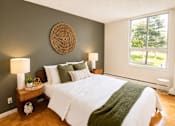 Thumbnail 3 of 11 - A bedroom with a white bed and a green blanket.