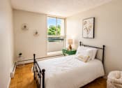 Thumbnail 6 of 11 - A bedroom with a large bed and a window overlooking a green area.