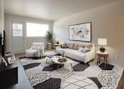 Thumbnail 20 of 24 - A living room with a white couch, a coffee table, and a large abstract painting on the wall.