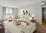 Thumbnail 7 of 9 - A living room with a white couch, a coffee table, and a painting on the wall.