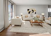 Thumbnail 3 of 9 - A living room with a white couch, a coffee table, and a painting on the wall.