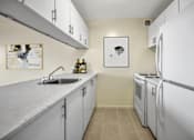 Thumbnail 4 of 14 - A kitchen with a sink, a refrigerator, and a microwave.