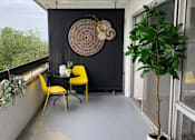 Thumbnail 7 of 8 - A balcony with a table and chairs and a potted plant.