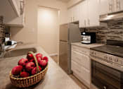 Thumbnail 18 of 24 - A kitchen with a refrigerator, oven, and sink.