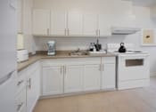 Thumbnail 5 of 8 - A white kitchen with a sink, stove, and oven.