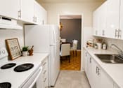 Thumbnail 9 of 11 - A kitchen with white appliances and cabinets.