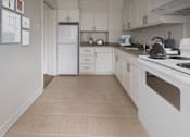 Thumbnail 4 of 8 - A kitchen with white appliances and cabinets.