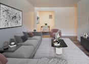 Thumbnail 16 of 24 - A living room with a grey couch, a coffee table, and a painting on the wall.