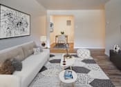 Thumbnail 24 of 24 - A living room with a white couch, a coffee table, and a large abstract painting on the wall.