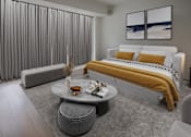 Thumbnail 1 of 8 - A modern bedroom with a large bed and a grey sofa.