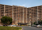 Thumbnail 2 of 22 - A large apartment complex with a parking lot in front.