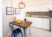 Thumbnail 10 of 24 - A kitchen with a table and chairs and a fridge.