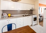 Thumbnail 11 of 24 - A kitchen with white cabinets and a blue chair.