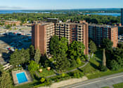 Thumbnail 1 of 20 - A large apartment complex with a pool and a parking lot.