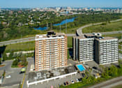 Thumbnail 2 of 9 - Two large buildings are situated next to a pool and a road.