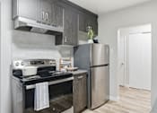 Thumbnail 16 of 34 - A modern kitchen with a stove, refrigerator, and a sink.