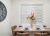 Thumbnail 5 of 34 - A dining table set with blue and white plates and a vase of flowers.
