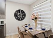 Thumbnail 1 of 34 - A dining room with a table set for two and a clock on the wall.
