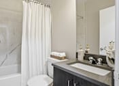 Thumbnail 9 of 34 - A bathroom with a marble patterned tub and a white shower curtain.