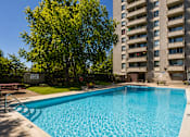 Thumbnail 11 of 11 - A blue swimming pool in front of a tall building.